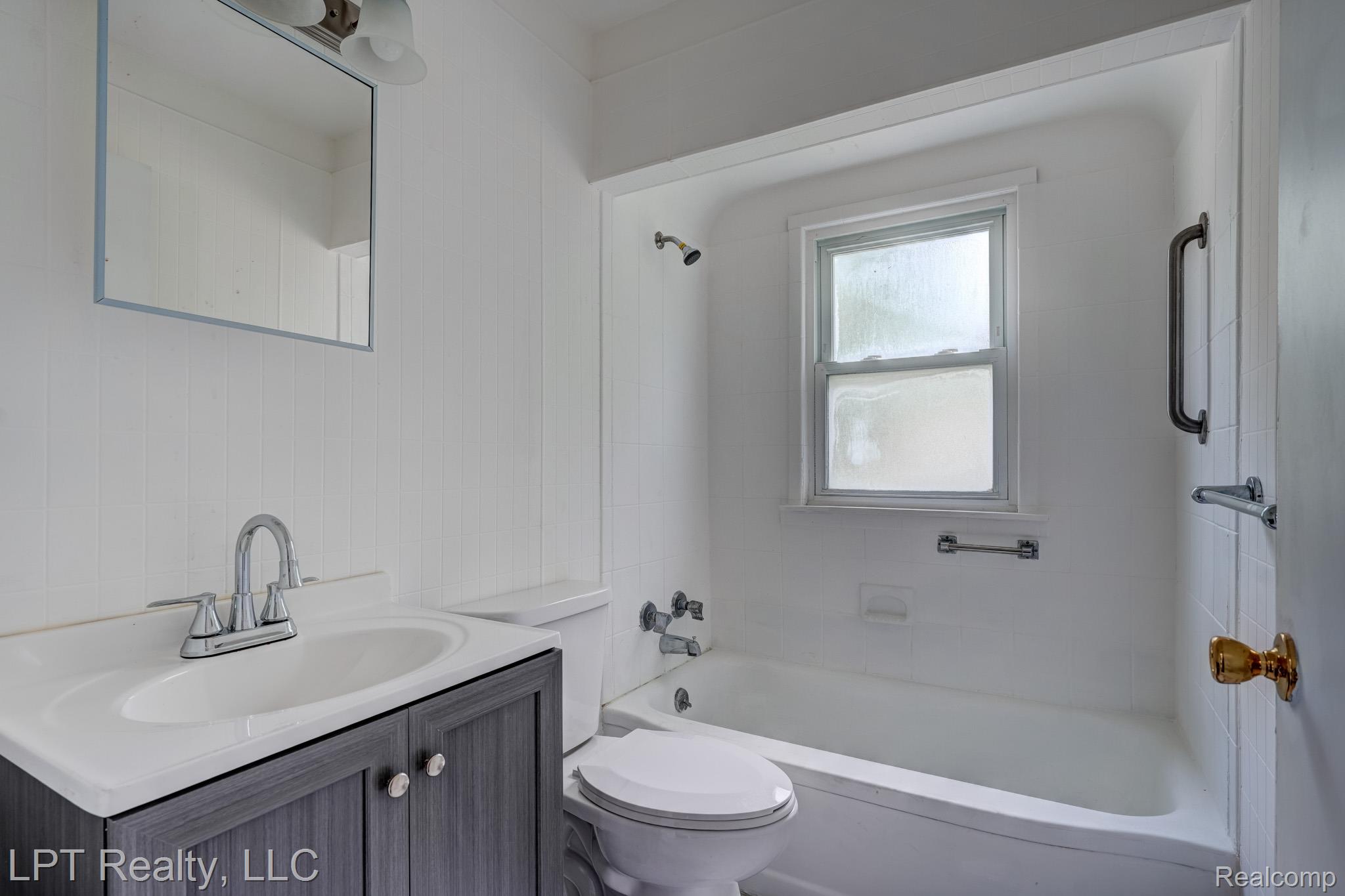 23038 Violet Street Farmington, MI 48336 - Photo 13 of 29 Bathroom featuring a vanity with a white countertop and gray wood-finish cabinetry, a white toilet, and a bathtub with a shower head and a window