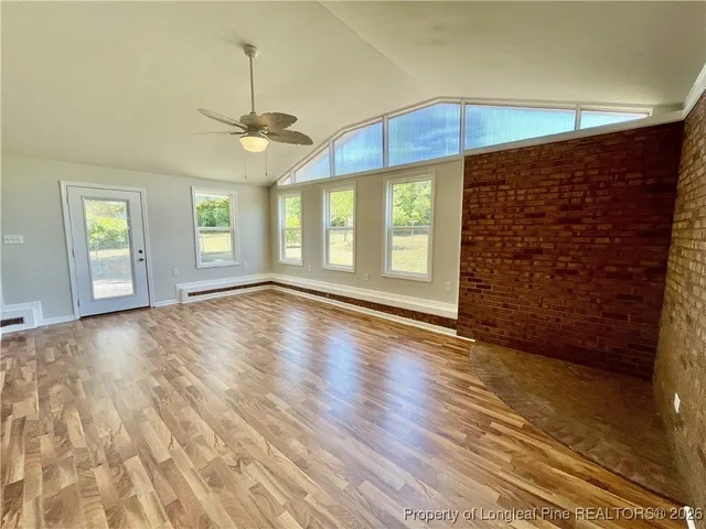 an empty room with wooden floor chandelier and windows