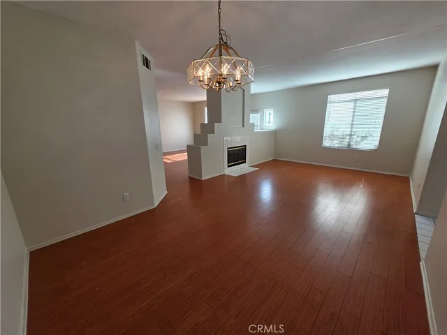 a view of a room with wooden floor fireplace and windows