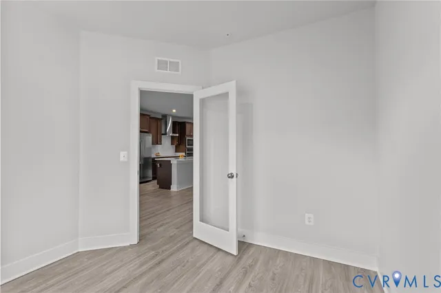 a view of a hallway with wooden floor and a kitchen