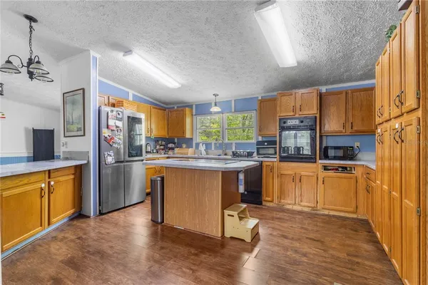 a kitchen with stainless steel appliances granite countertop a refrigerator a sink dishwasher a stove with wooden cabinets and floor