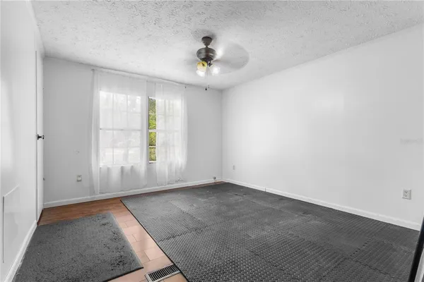 an empty room with windows and ceiling fan