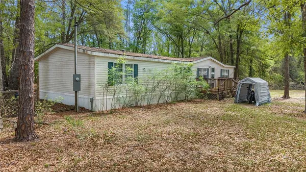 a view of a house with a yard and large trees