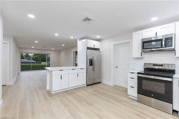 a large kitchen with stainless steel appliances kitchen island granite countertop a stove and a sink