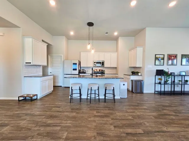 a kitchen with kitchen island granite countertop a sink a counter top space cabinets and stainless steel appliances
