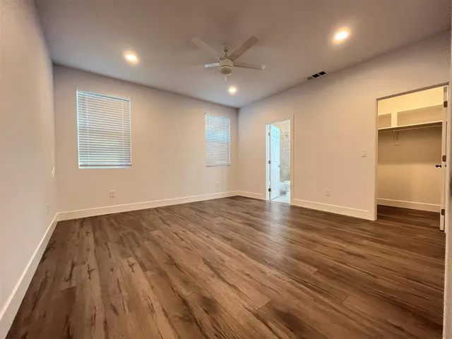 an empty room with wooden floor and a ceiling fan