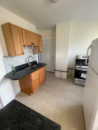 a kitchen with granite countertop a sink a stove and a refrigerator