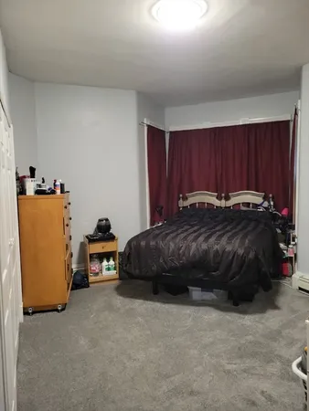 a bedroom with a bed and a refrigerator