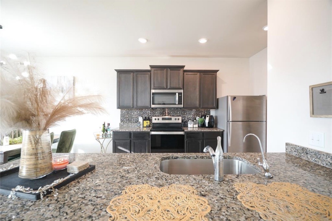 7943 Vacek Meadows Loop Richmond, TX 77469 - Photo 13 of 36 a kitchen with stainless steel appliances granite countertop a stove refrigerator and cabinets