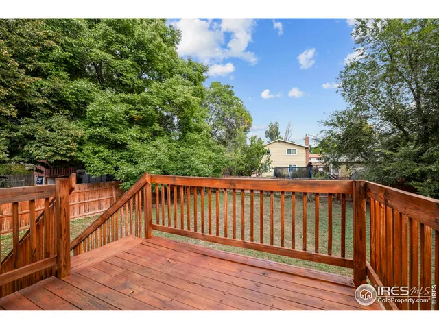 a balcony with wooden floor and trees in the background