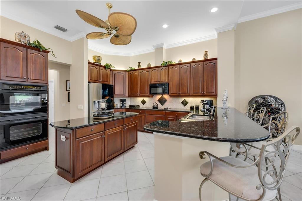 1624 Manchester Court Naples, FL 34109 - Photo 14 of 30 a kitchen with kitchen island granite countertop a stove cabinets and a sink