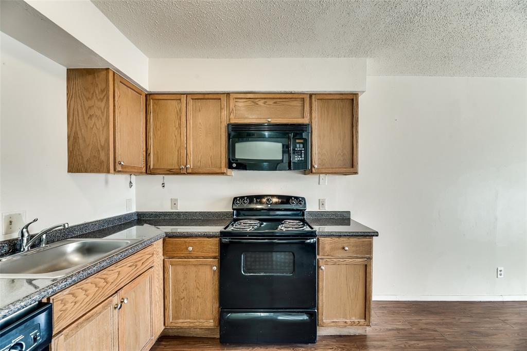 106 East Cedar Street, Unit 12 Arlington, TX 76011 - Photo 10 of 18 a kitchen with stainless steel appliances granite countertop a stove a sink and a microwave