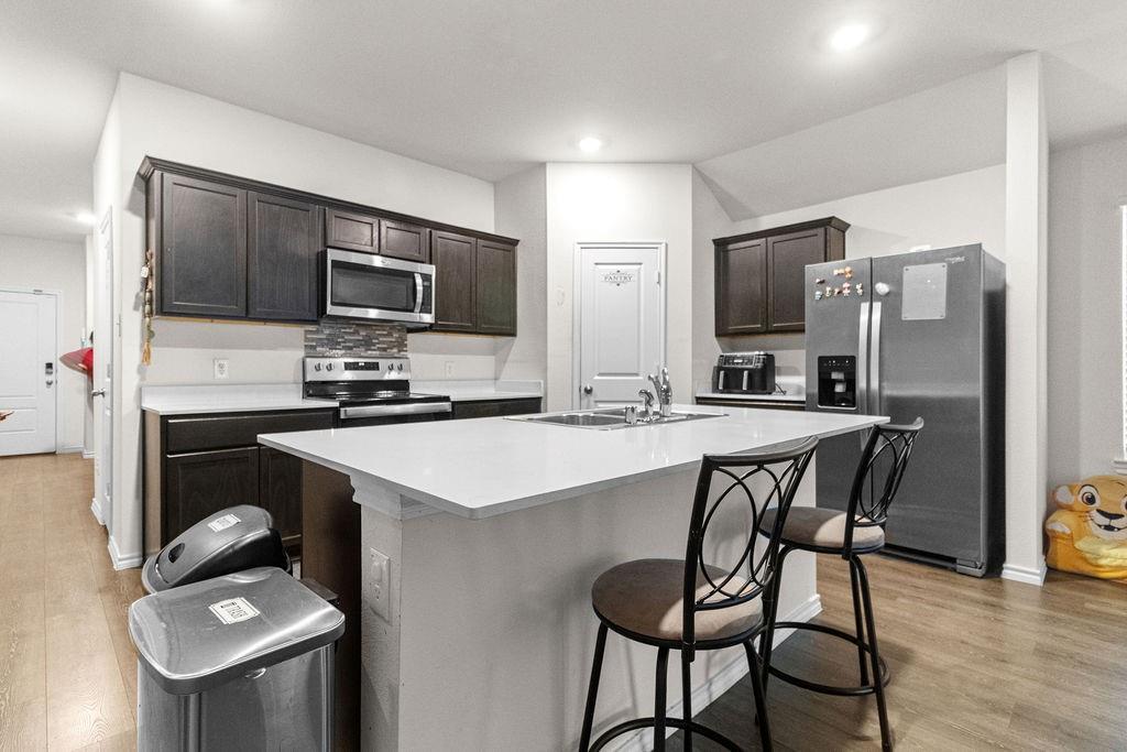 2928 Roper Street Royse City, TX 75189 - Photo 10 of 26 a kitchen with kitchen island granite countertop a stove refrigerator and microwave with wooden floor