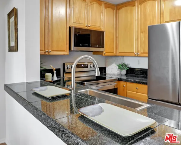 a kitchen with granite countertop a sink a stove top oven and cabinetry