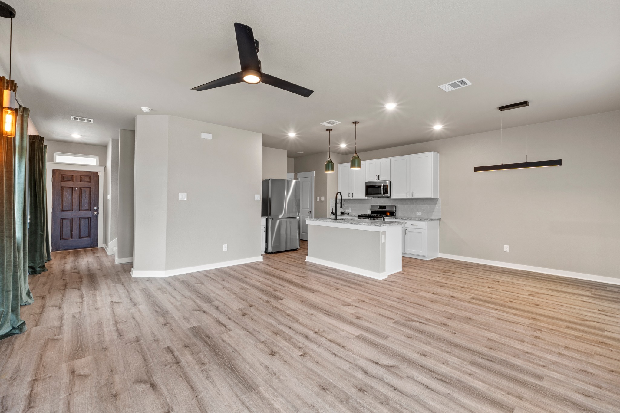 2251 Rocoso Trail Leander, TX 78641 - Photo 6 of 34 Gleaming wood-inspired floors flow through a light-filled, open-concept kitchen and living area.