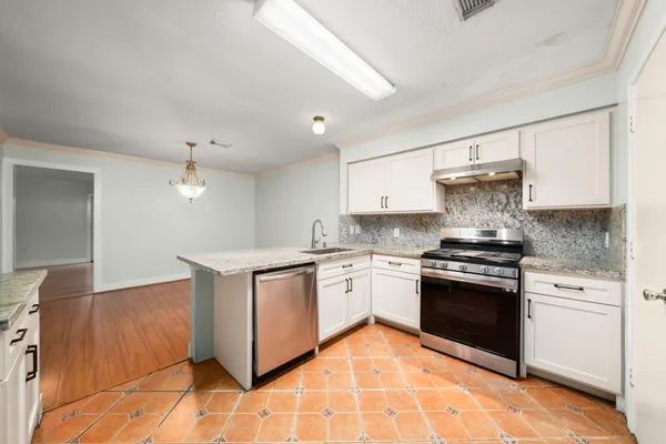 a kitchen with stainless steel appliances granite countertop a stove a sink and a microwave