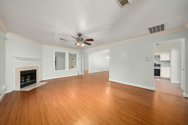 a view of an empty room with wooden floor and a fireplace