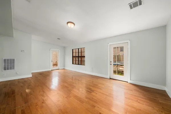 a view of an empty room with window and wooden floor