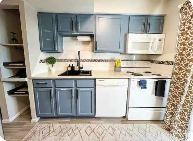 a kitchen with granite countertop a stove a sink and wooden cabinets