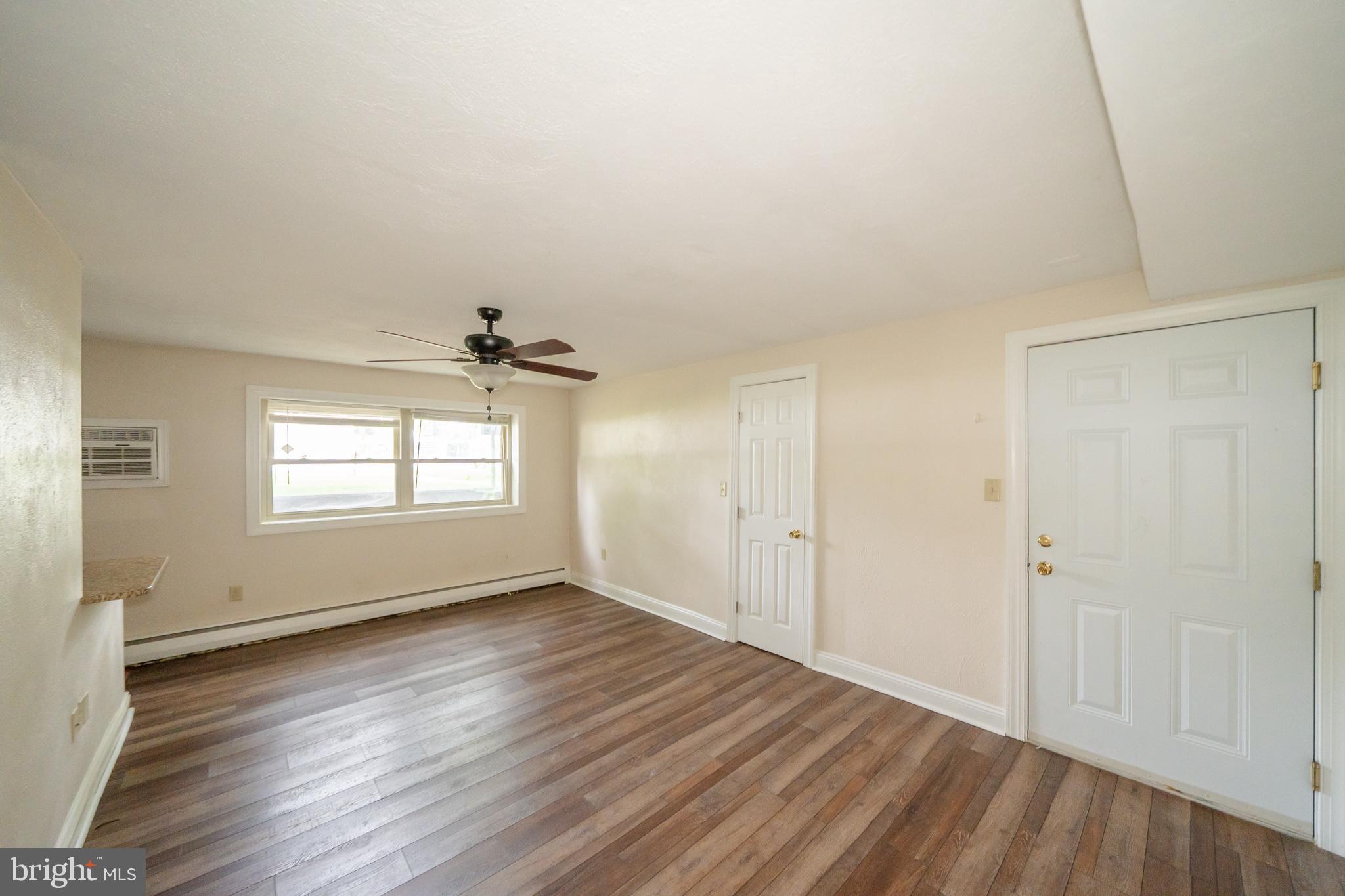 231 Sharpless Street, Unit 1D West Chester, PA 19382 - Photo 9 of 11 an empty room with wooden floor chandelier fan and windows