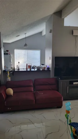 a living room with furniture a flat screen tv and kitchen view