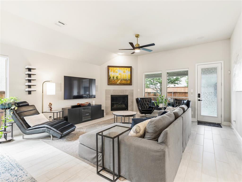 15340 Crape Myrtle Road Frisco, TX 75035 - Photo 14 of 40 Bright living space featuring light wood-finish flooring, a contemporary fireplace with a stone surround, and multiple windows