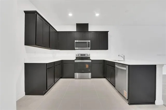 a kitchen with stainless steel appliances kitchen island granite countertop a refrigerator and a stove top oven