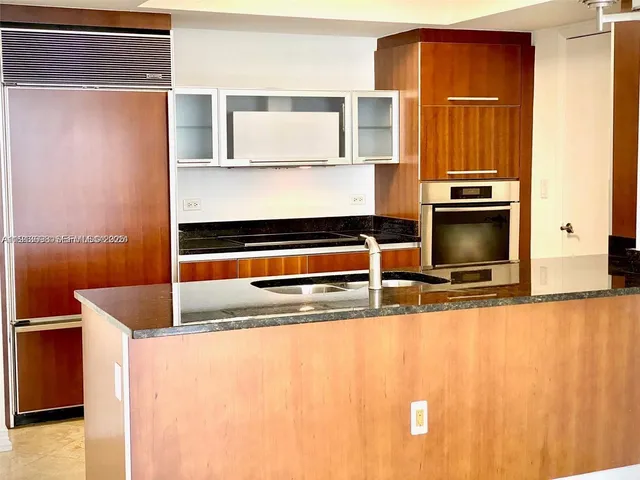 a kitchen with granite countertop a sink and a stove top oven