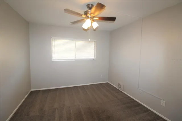 an empty room with a window and a fan
