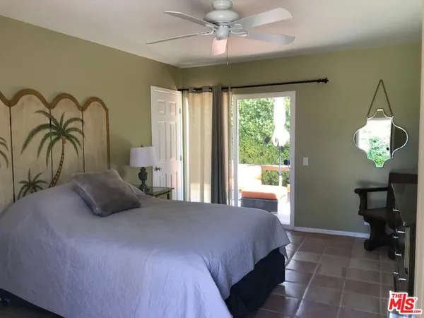 a bedroom with a bed a chandelier and a large window
