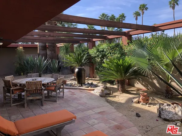 a view of a patio with table and chairs potted plants and palm trees
