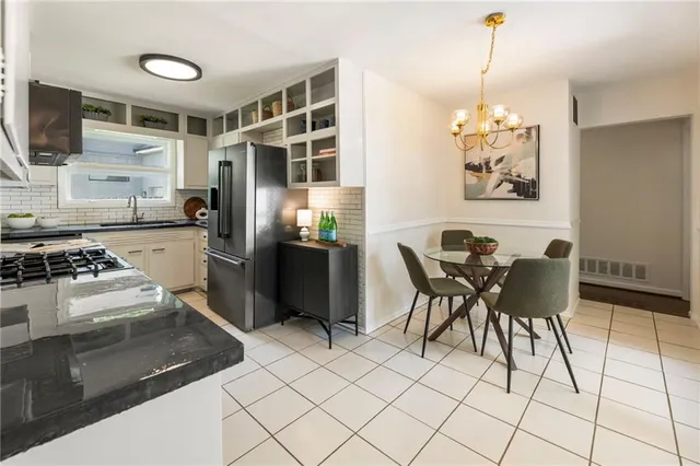 a kitchen with stainless steel appliances granite countertop a stove a refrigerator and a dining table with wooden floor