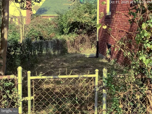 a view of a yard with plants and brick wall