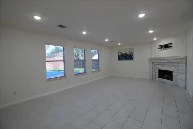 an empty room with windows and fireplace