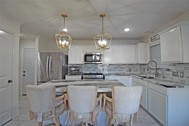 a kitchen with stainless steel appliances granite countertop a sink a stove a refrigerator with a dining table and chairs