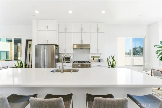 a kitchen with stainless steel appliances kitchen island granite countertop a sink and a refrigerator