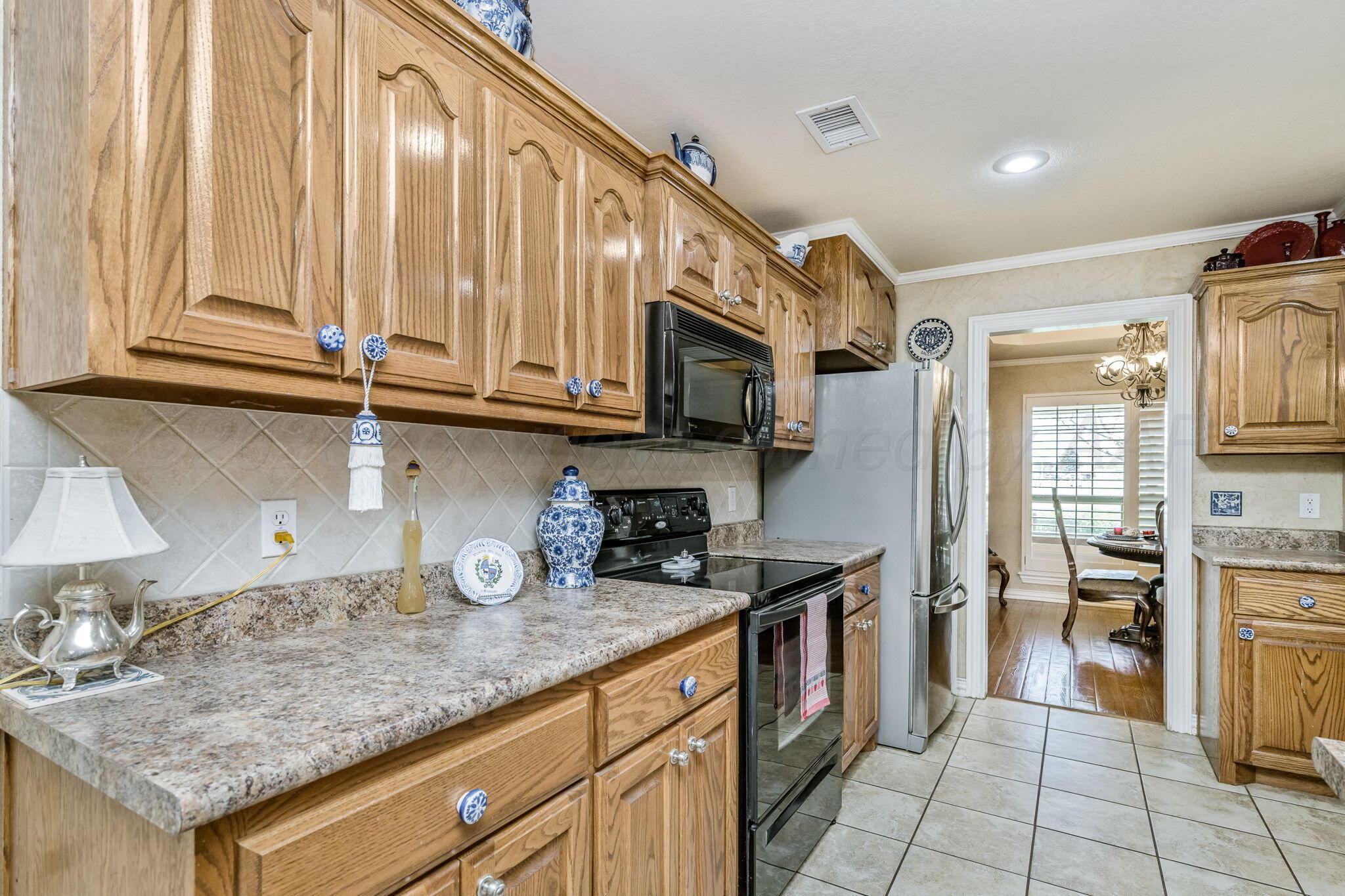 6007 Hunter Drive Amarillo, TX 79119 - Photo 11 of 28 a kitchen with granite countertop a sink a stove and cabinets