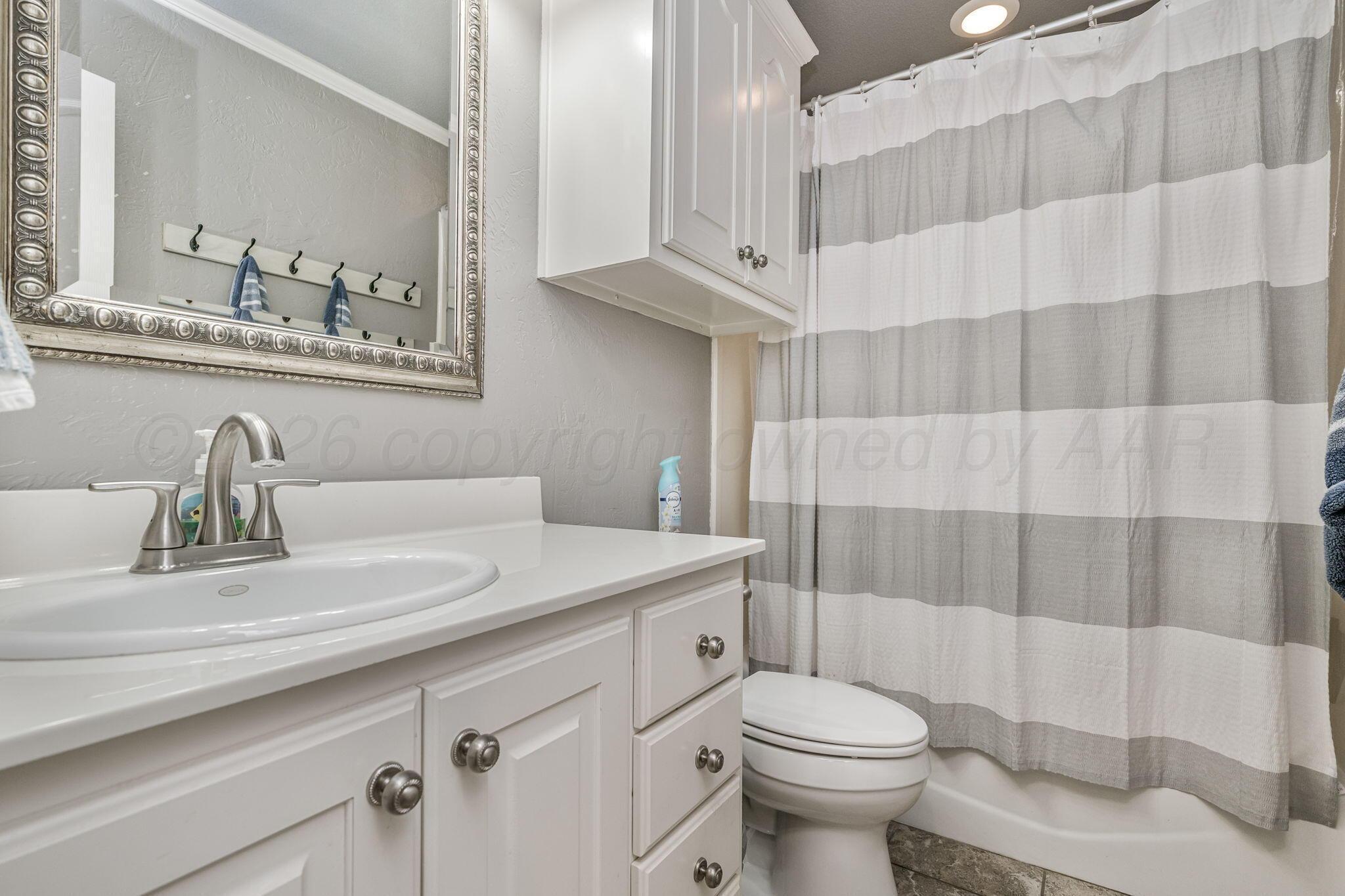 6007 Hunter Drive Amarillo, TX 79119 - Photo 22 of 28 a bathroom with a sink a toilet and shower