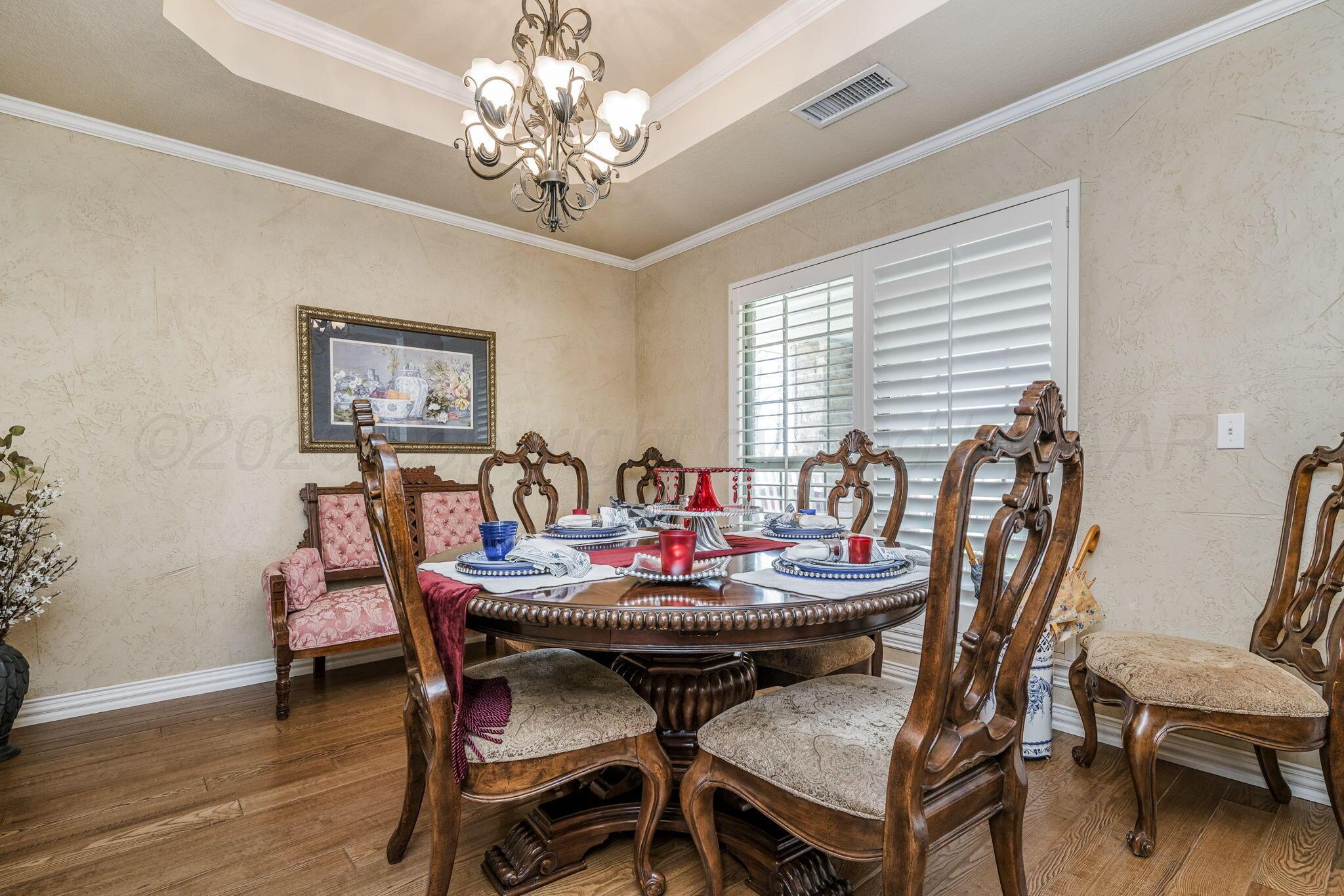 6007 Hunter Drive Amarillo, TX 79119 - Photo 9 of 28 a dining room with furniture a chandelier and wooden floor