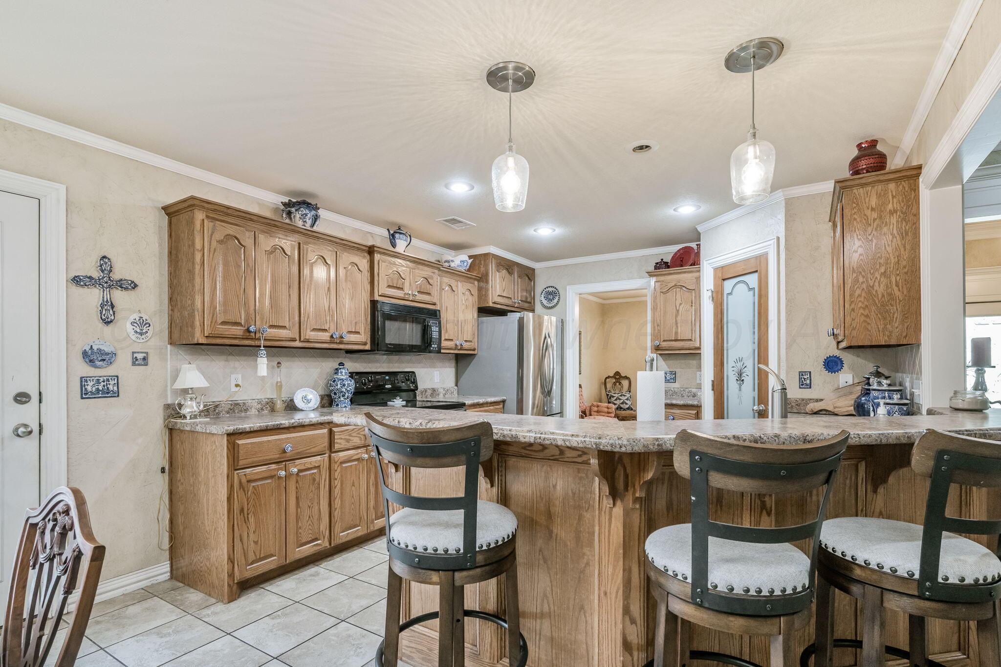 6007 Hunter Drive Amarillo, TX 79119 - Photo 10 of 28 a kitchen with a dining table chairs sink and cabinets