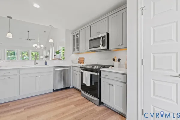 a kitchen with stainless steel appliances granite countertop white cabinets a sink a stove a window and white