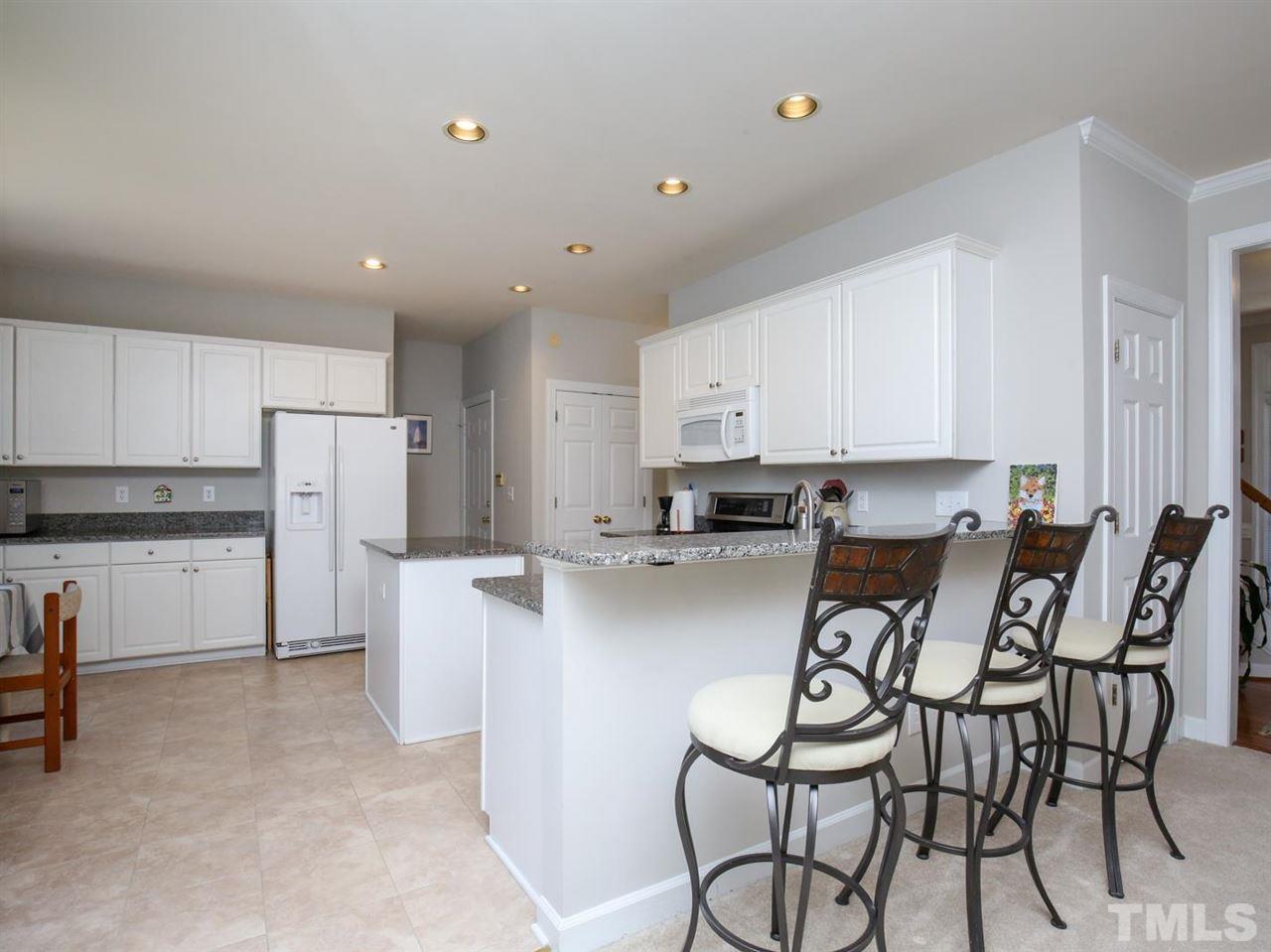 2329 Finley Ridge Lane Raleigh, NC 27615 - Photo 9 of 27 a kitchen with stainless steel appliances granite countertop a white table and chairs in it