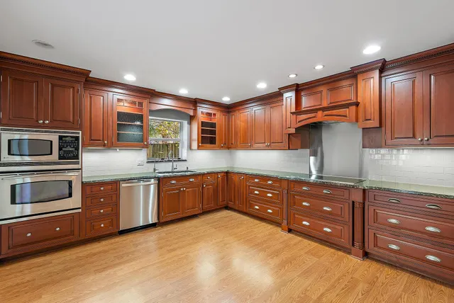 a kitchen with stainless steel appliances granite countertop wooden cabinets and a stove top oven