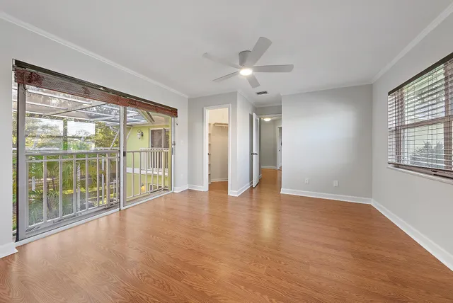 a view of an empty room with a window and wooden floor