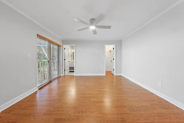 an empty room with wooden floor and windows