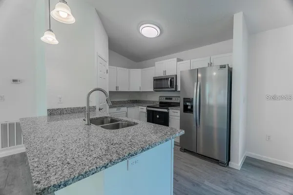 a kitchen with stainless steel appliances granite countertop a sink stove and refrigerator
