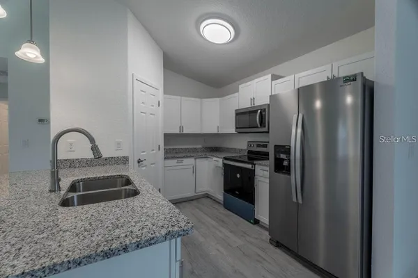 a kitchen with granite countertop a refrigerator and a sink