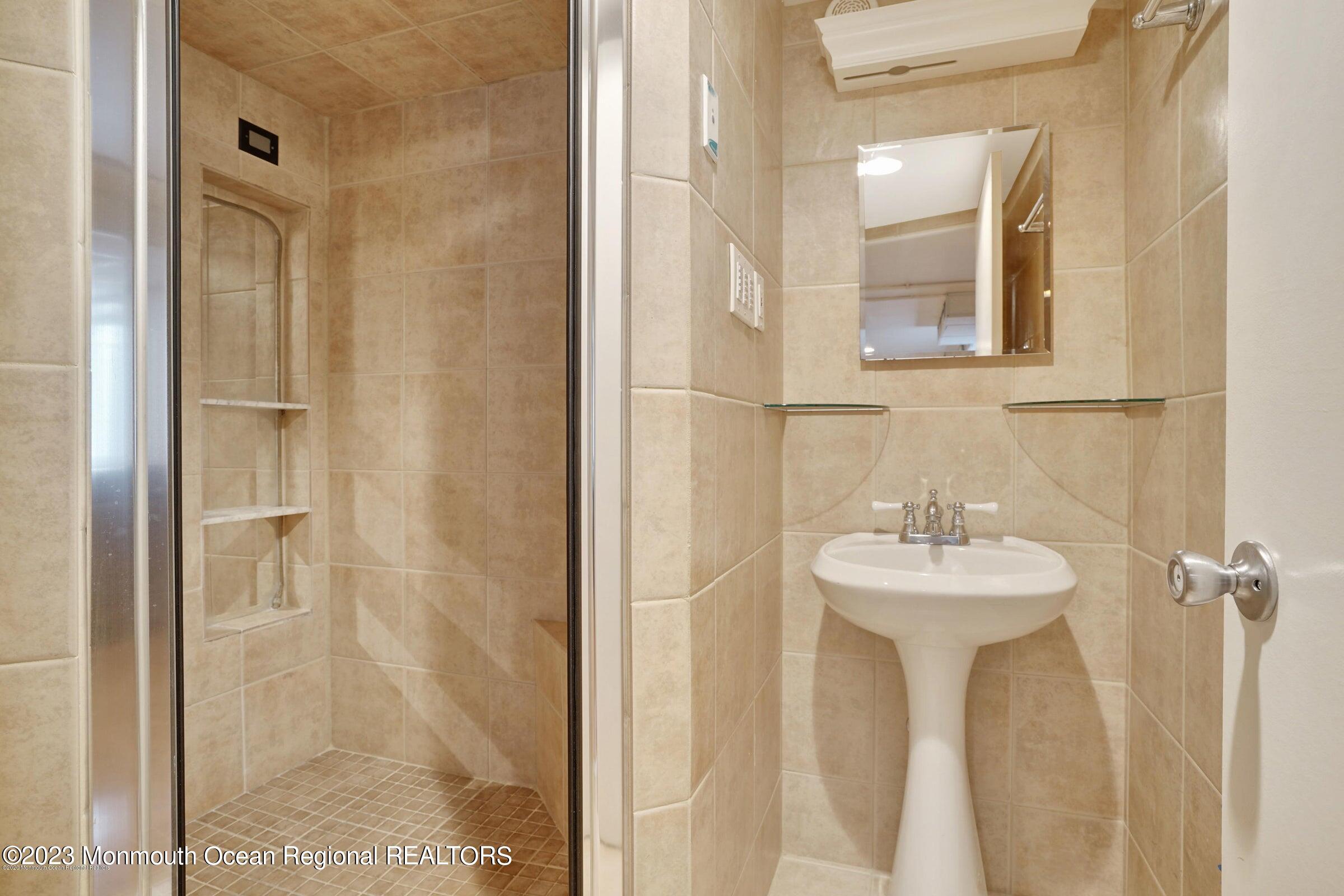 77 Pinewood Avenue West Long Branch, NJ 07764 - Photo 16 of 25 a bathroom with a sink a mirror and shower