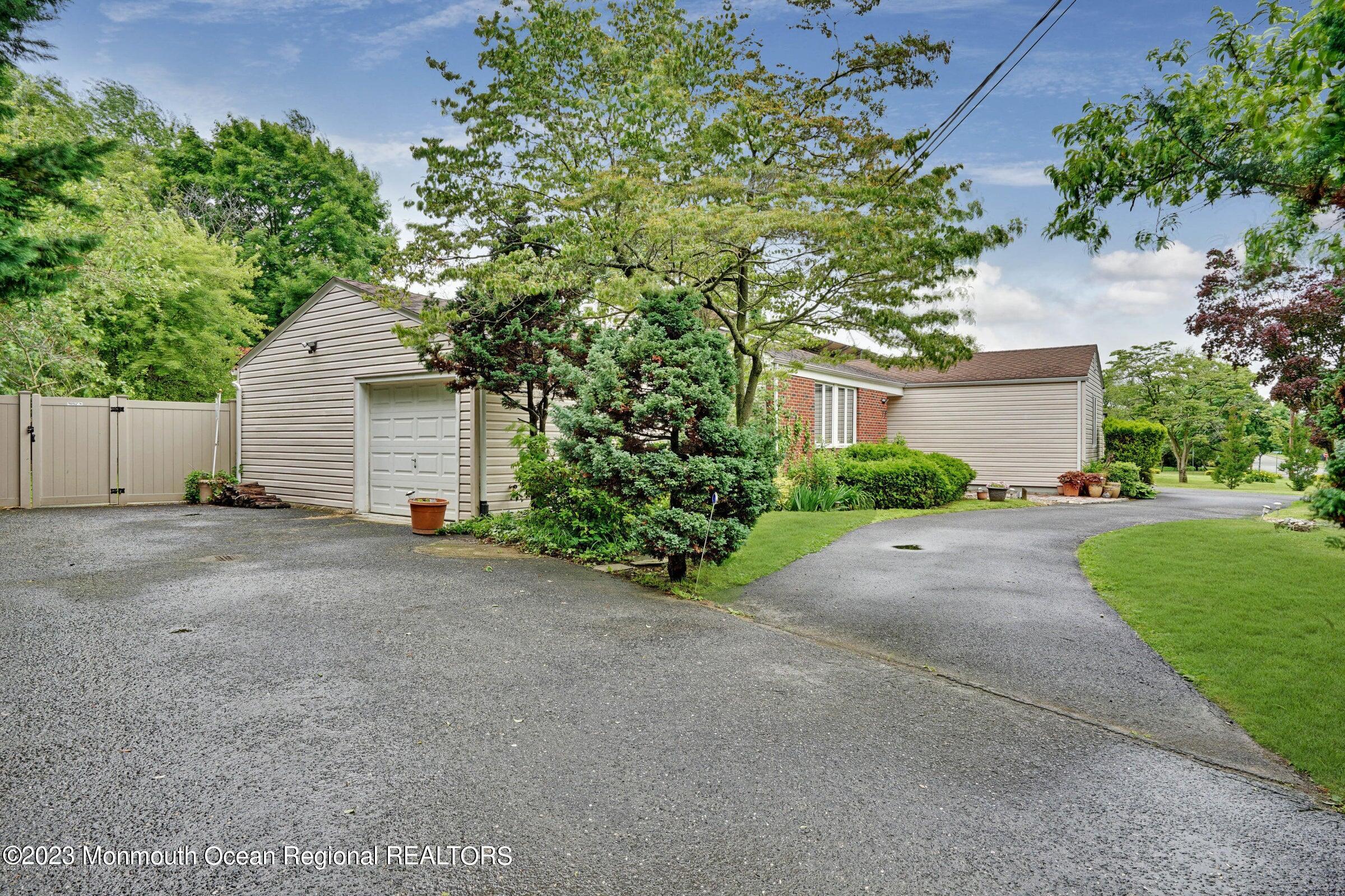 77 Pinewood Avenue West Long Branch, NJ 07764 - Photo 2 of 25 a front view of a house with a garden and trees