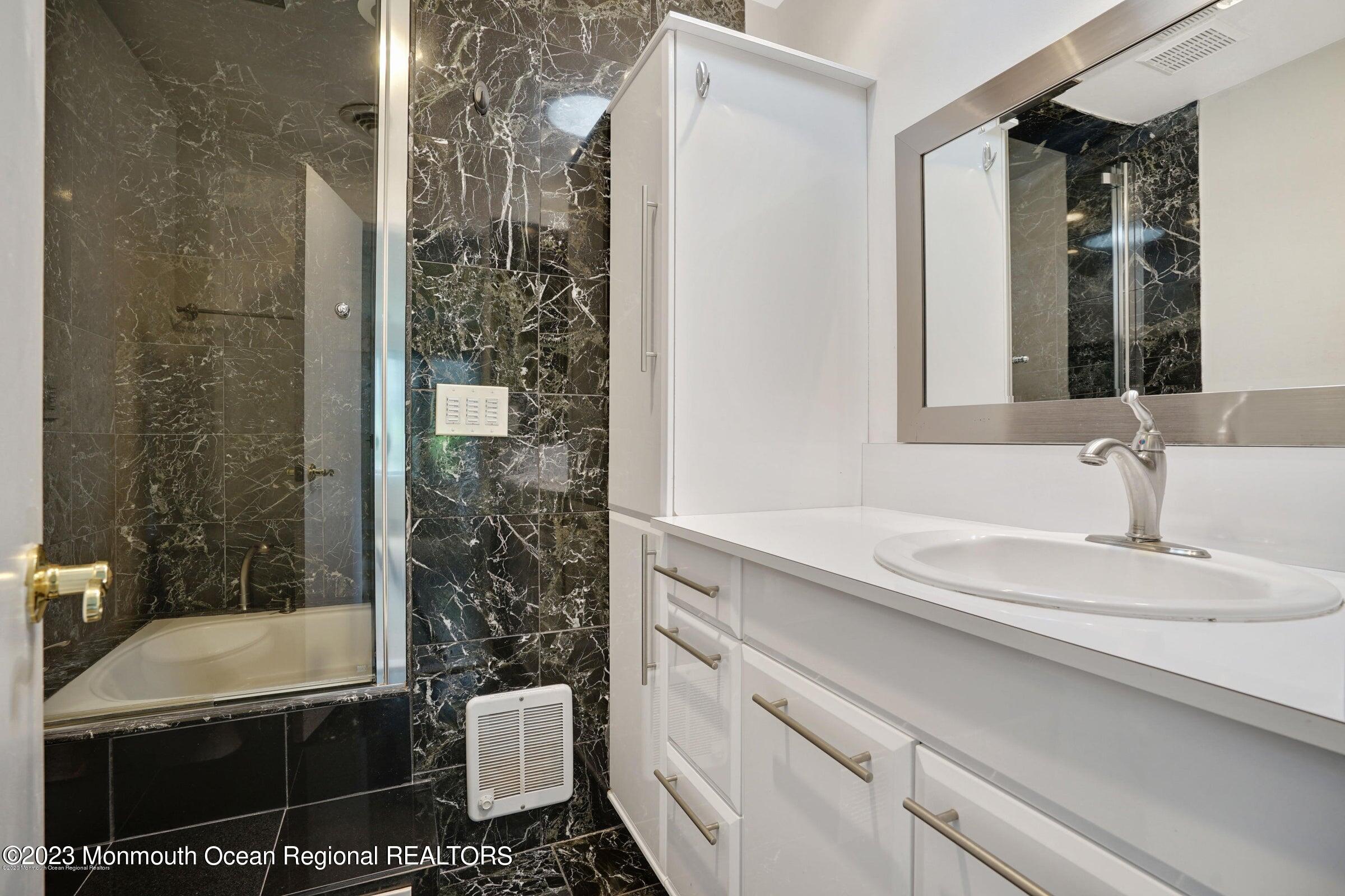 77 Pinewood Avenue West Long Branch, NJ 07764 - Photo 9 of 25 a bathroom with a granite countertop sink a toilet and shower